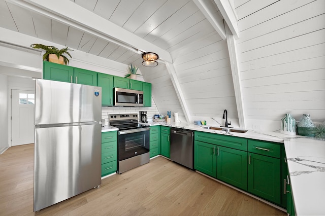 kitchen with appliances with stainless steel finishes, a sink, lofted ceiling with beams, light wood finished floors, and green cabinetry