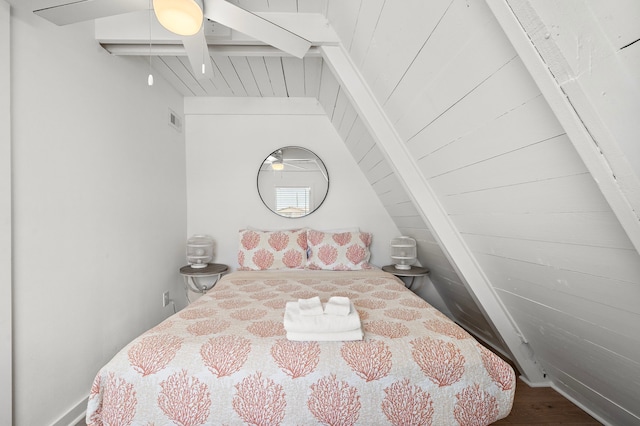 bedroom with vaulted ceiling with beams, wood finished floors, and visible vents