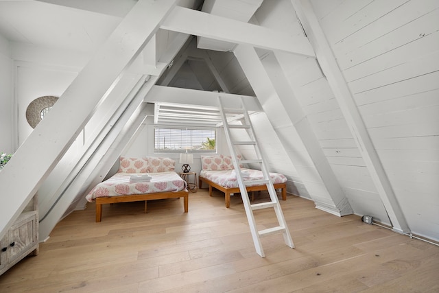 bedroom with light wood-style floors and vaulted ceiling with beams