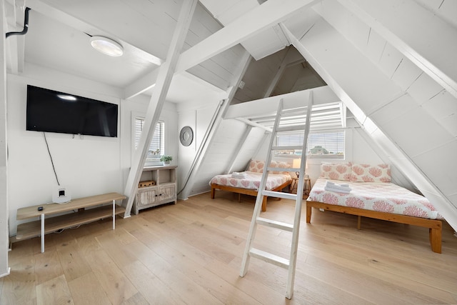 bedroom with vaulted ceiling with beams, multiple windows, and light wood-type flooring