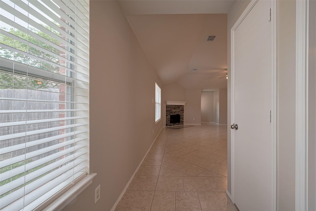 hallway featuring visible vents, baseboards, lofted ceiling, and light tile patterned floors