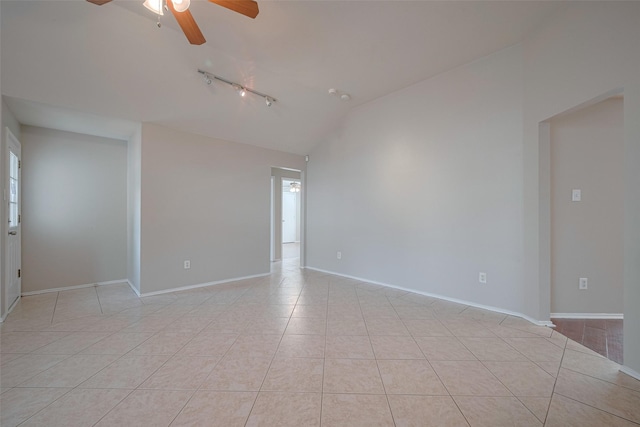 empty room with ceiling fan, light tile patterned floors, track lighting, baseboards, and lofted ceiling
