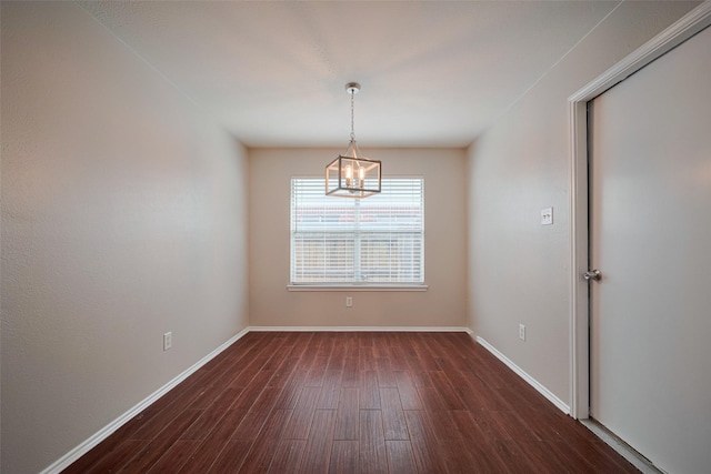 empty room featuring dark wood-style flooring, baseboards, and a chandelier