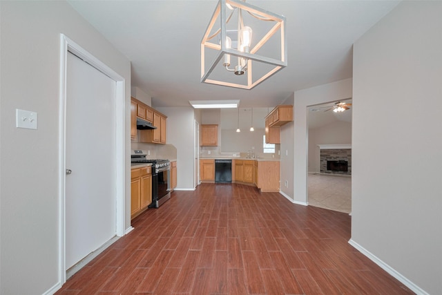 kitchen featuring a fireplace, black dishwasher, under cabinet range hood, ceiling fan with notable chandelier, and gas stove