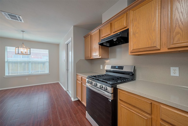 kitchen with dark wood-style flooring, stainless steel gas stove, light countertops, under cabinet range hood, and visible vents