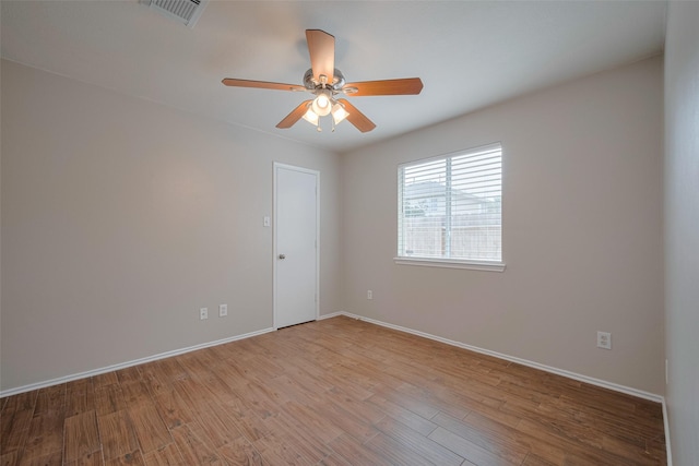 empty room featuring visible vents, light wood-style flooring, ceiling fan, and baseboards