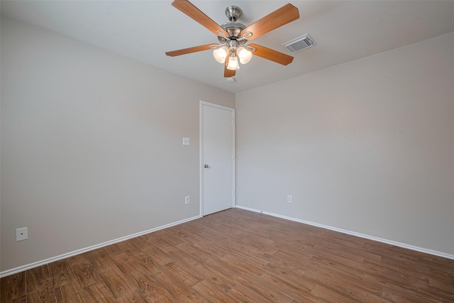 spare room featuring baseboards, a ceiling fan, wood finished floors, and visible vents