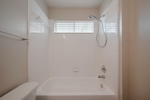 bathroom with toilet, a textured wall, and shower / washtub combination
