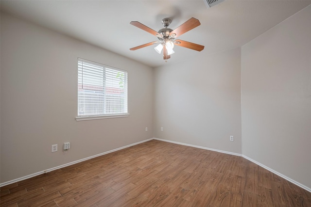unfurnished room featuring baseboards, ceiling fan, wood finished floors, and visible vents