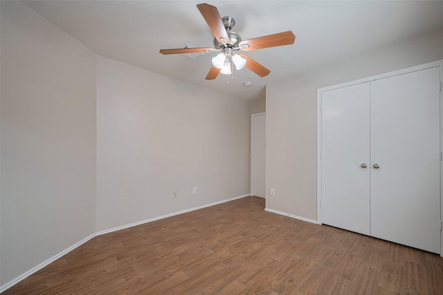 unfurnished bedroom with baseboards, a ceiling fan, wood finished floors, and a closet
