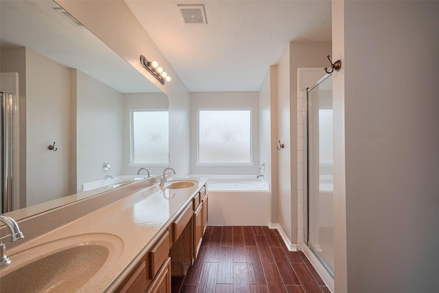 bathroom featuring visible vents, a sink, a bath, and a stall shower