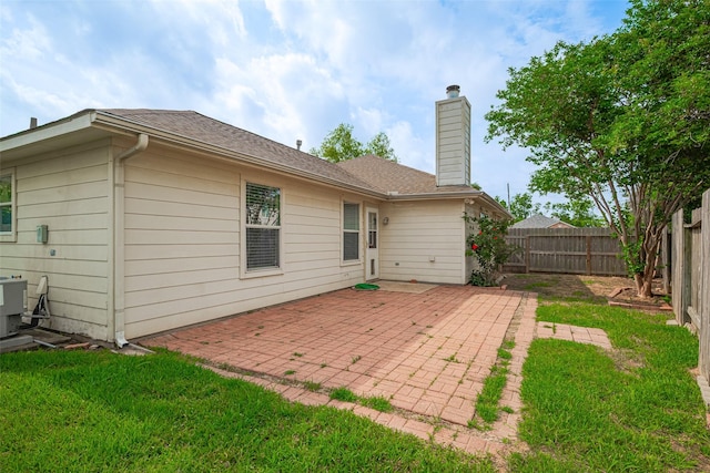 back of property featuring central AC, a patio, a fenced backyard, a chimney, and a yard