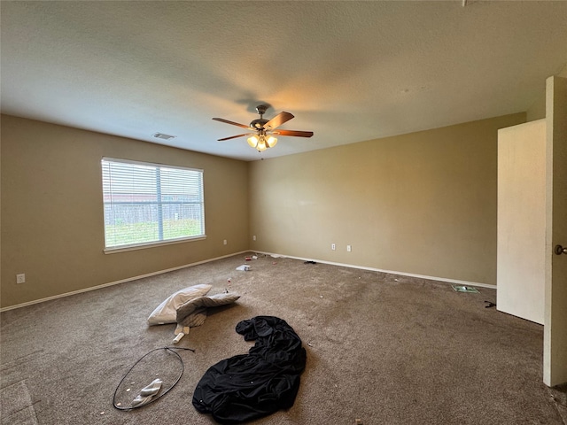 carpeted spare room with baseboards, ceiling fan, and visible vents