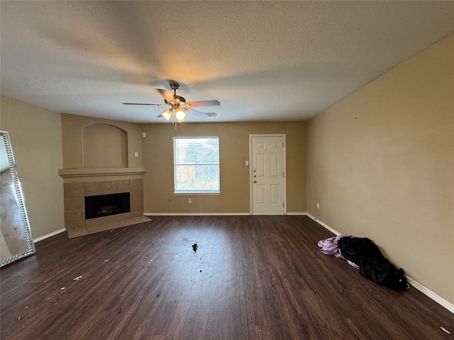 unfurnished living room featuring wood finished floors, baseboards, a textured ceiling, a tile fireplace, and a ceiling fan