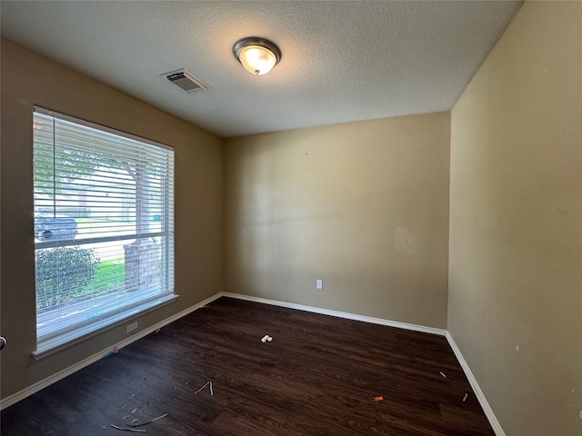 empty room with visible vents, baseboards, wood finished floors, and a wealth of natural light