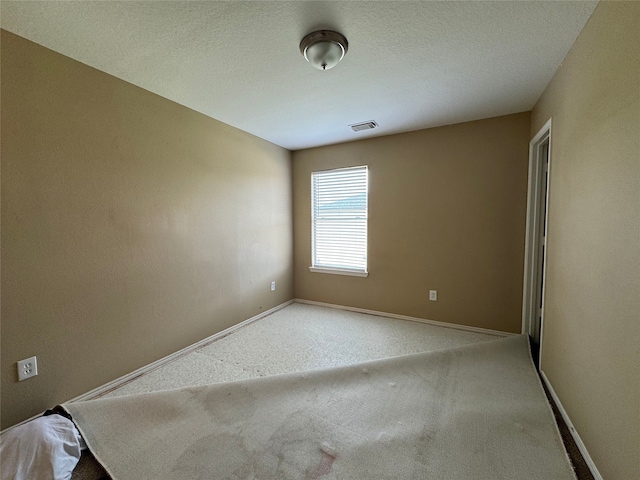 spare room with carpet floors, baseboards, and visible vents
