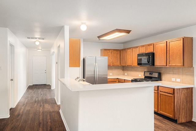 9607 Western Briar Ln, Humble, TX 77396 - kitchen featuring appliances with stainless steel finishes, brown cabinetry, a peninsula, and backsplash