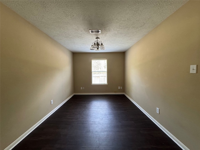 unfurnished dining area with a textured ceiling, visible vents, baseboards, a notable chandelier, and dark wood-type flooring
