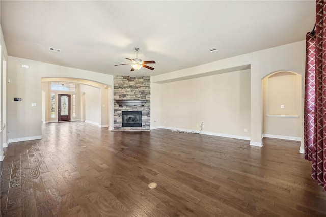 25034 Jennifer Heights Ct, Spring, TX 77389 - unfurnished living room with ceiling fan, a stone fireplace, visible vents, arched walkways, and dark wood-style floors