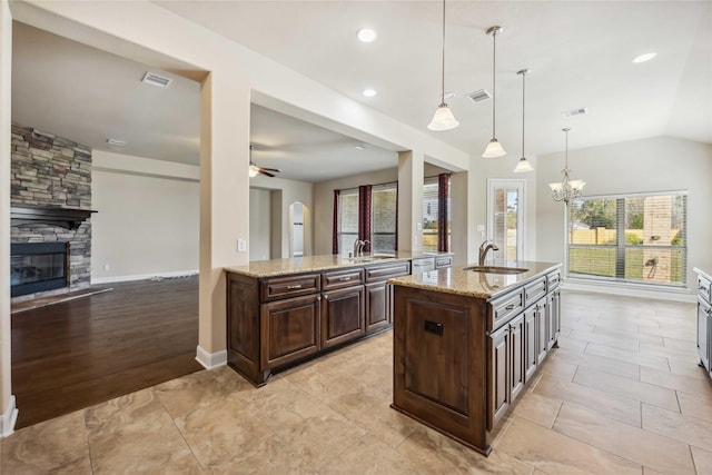 25034 Jennifer Heights Ct, Spring, TX 77389 - kitchen with a sink, light stone counters, a fireplace, and visible vents