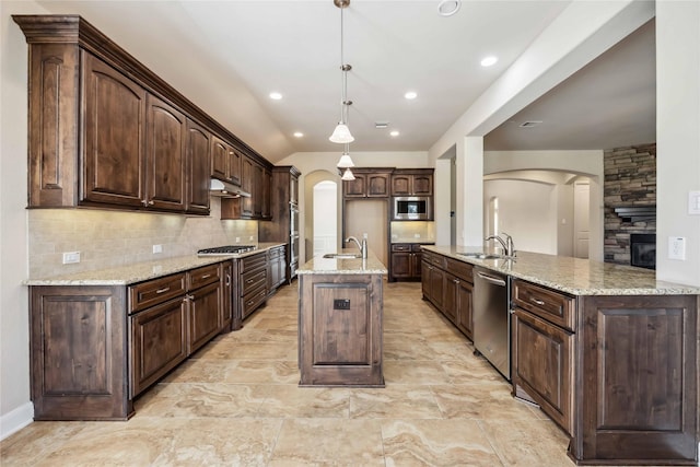 25034 Jennifer Heights Ct, Spring, TX 77389 - kitchen featuring appliances with stainless steel finishes, a sink, arched walkways, an island with sink, and under cabinet range hood
