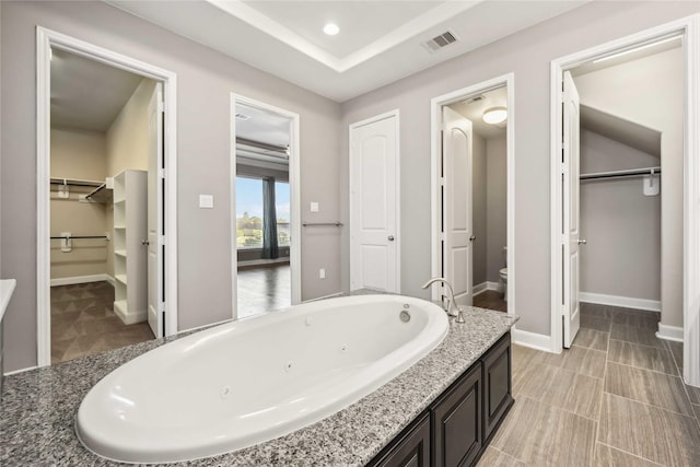 25034 Jennifer Heights Ct, Spring, TX 77389 - full bathroom featuring visible vents, baseboards, a whirlpool tub, toilet, and a spacious closet