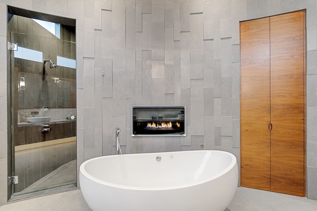 15618 Oyster Cove Dr, Sugar Land, TX 77478 - bathroom featuring a freestanding bath, tile patterned flooring, a glass covered fireplace, and a shower