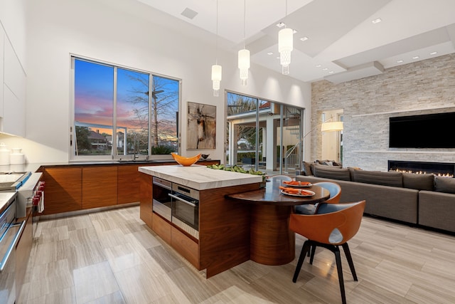 15618 Oyster Cove Dr, Sugar Land, TX 77478 - kitchen featuring modern cabinets, brown cabinets, a towering ceiling, hanging light fixtures, and open floor plan
