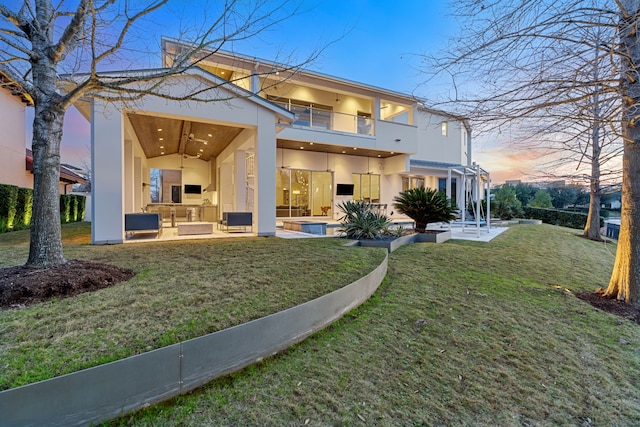 15618 Oyster Cove Dr, Sugar Land, TX 77478 - back of property at dusk featuring stucco siding, a balcony, a yard, a patio area, and a ceiling fan