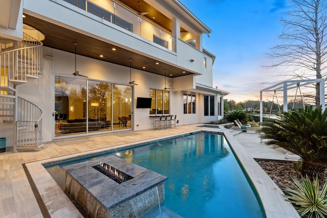 15618 Oyster Cove Dr, Sugar Land, TX 77478 - rear view of property with a patio area, an outdoor pool, stucco siding, a balcony, and a fire pit