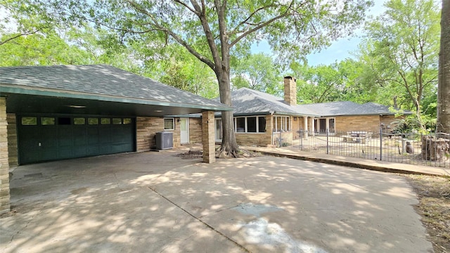 ranch-style home featuring fence, a chimney, a shingled roof, concrete driveway, and an attached garage