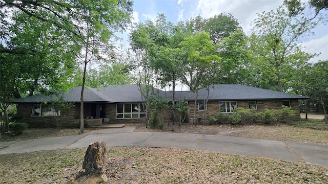 ranch-style house with concrete driveway and stone siding