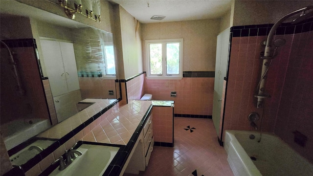 full bath with tile patterned flooring, vanity, a wainscoted wall, tile walls, and visible vents