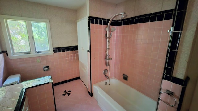 bathroom with tile patterned flooring, wainscoting, bathtub / shower combination, and tile walls