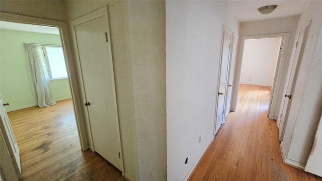 hallway featuring baseboards and light wood finished floors