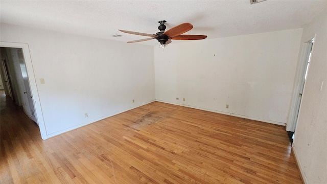 unfurnished room featuring a ceiling fan, baseboards, a textured ceiling, and light wood-type flooring