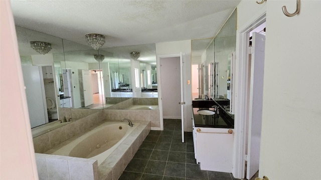 bathroom featuring tile patterned floors, vanity, a tub with jets, and a textured ceiling