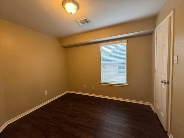 spare room with visible vents, baseboards, and dark wood-type flooring