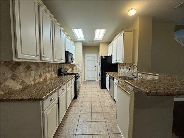 kitchen featuring decorative backsplash, a sink, black appliances, a peninsula, and light tile patterned flooring