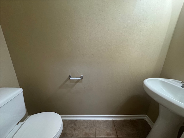 bathroom featuring baseboards, a sink, tile patterned flooring, and toilet