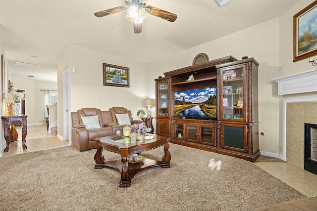 living area featuring baseboards, ceiling fan, light tile patterned flooring, and a tile fireplace