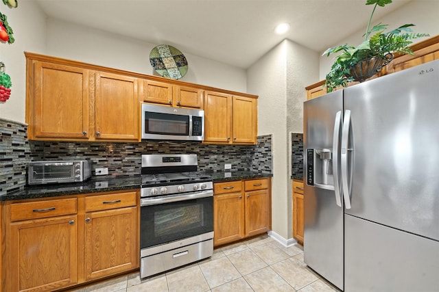 kitchen with a toaster, appliances with stainless steel finishes, decorative backsplash, and light tile patterned floors