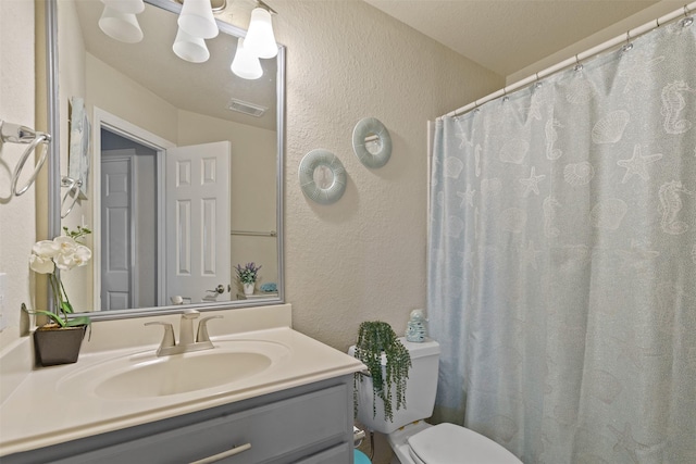 bathroom featuring visible vents, a textured wall, toilet, and vanity