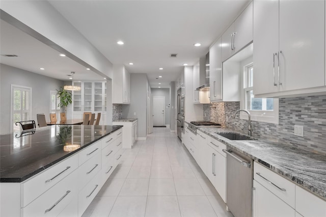 kitchen with decorative backsplash, appliances with stainless steel finishes, a sink, recessed lighting, and wall chimney exhaust hood