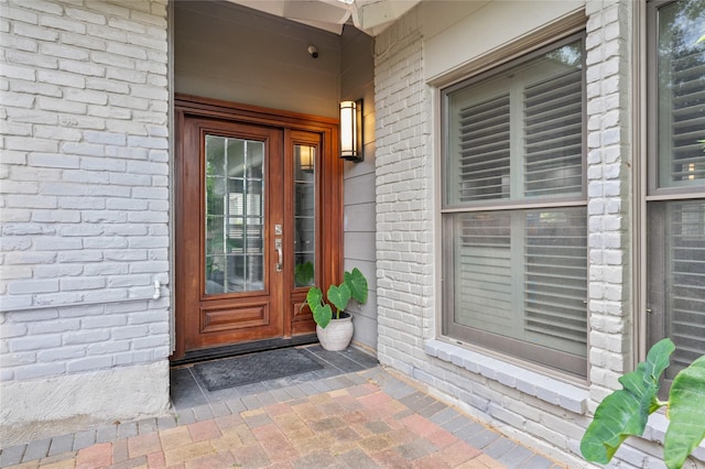 entrance to property with covered porch and brick siding