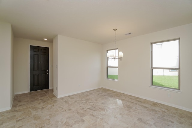 spare room with baseboards, a chandelier, and visible vents