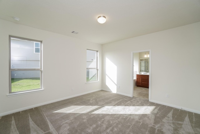 empty room featuring baseboards, light carpet, and visible vents