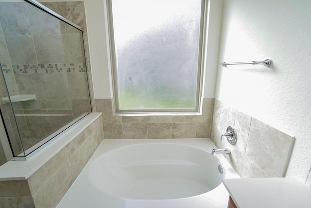 bathroom with a tile shower and a garden tub