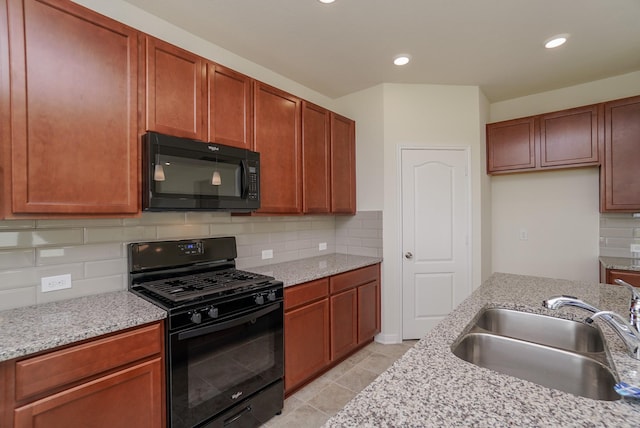 kitchen with a sink, backsplash, black appliances, and light stone countertops