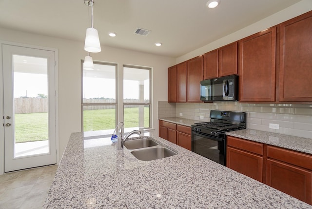 kitchen featuring backsplash, visible vents, hanging light fixtures, a sink, and black appliances